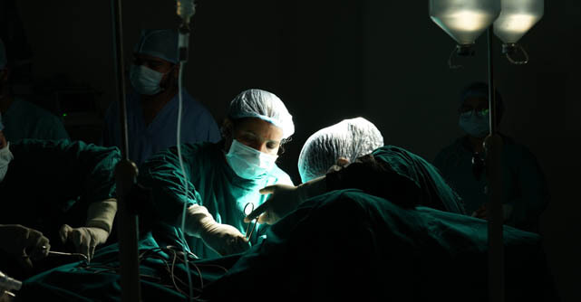 Surgical team performing an operation in a dimly lit operating room